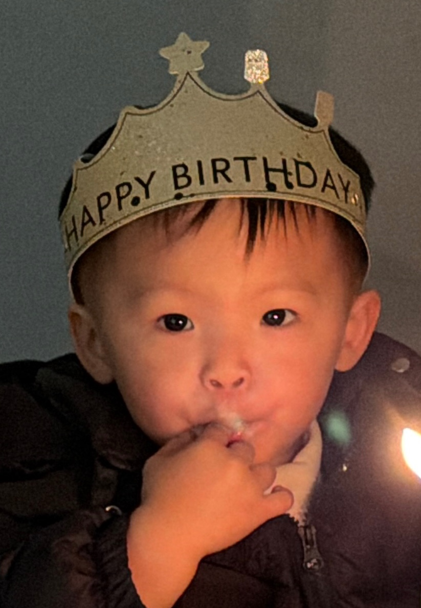 图片展示了一个戴着“HAPPY BIRTHDAY”生日帽的小孩。小孩穿着黑色外套,手放在嘴边,背景为深色。图片位于介绍转像素等工序耗时的上下文之后,直观呈现了了转像素等工序中需要在电脑前手动画出来的场景,与上下文提到的“把图片转成像素画”相呼应,形象地展示了这一工序的耗时性。